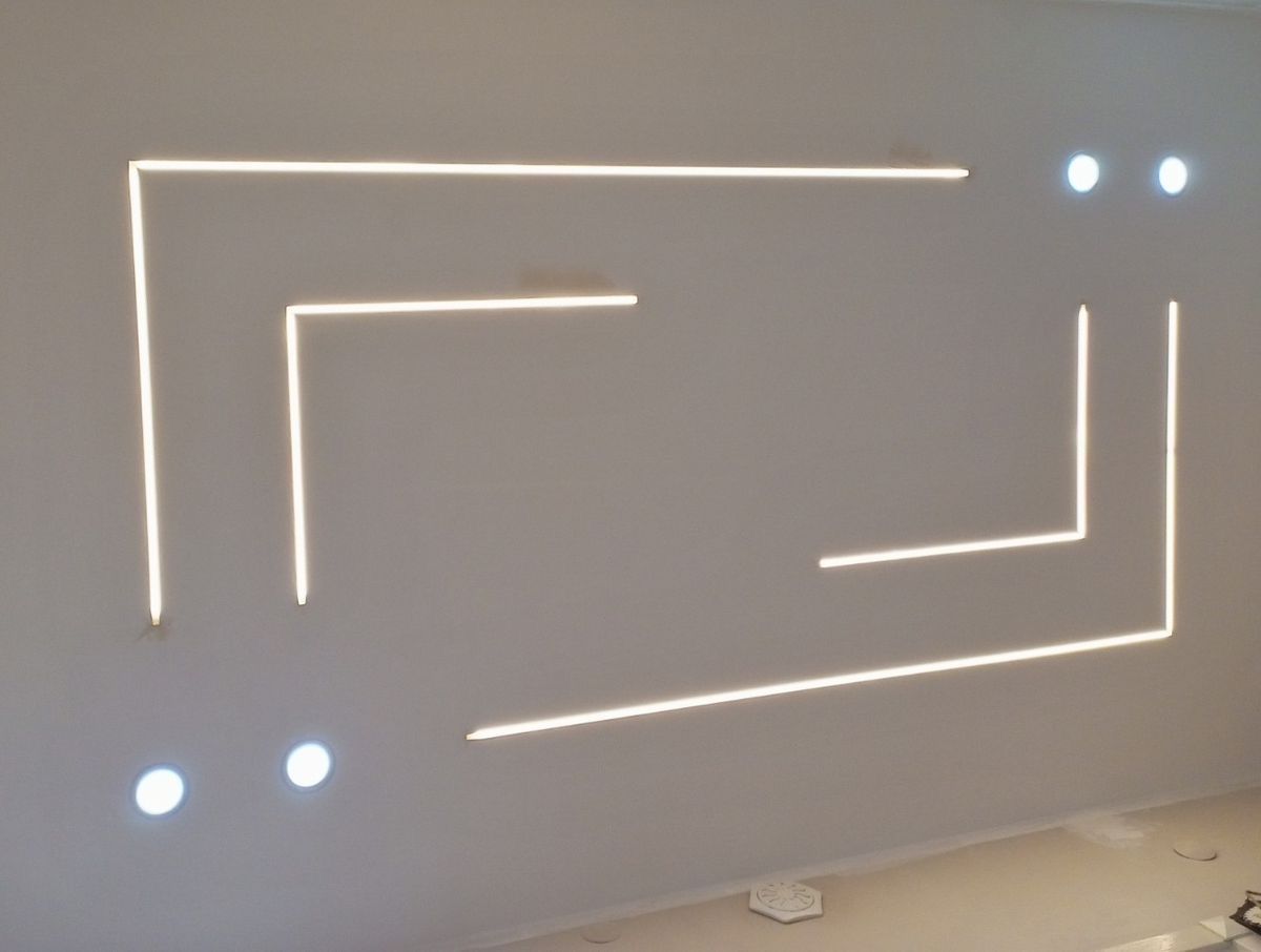 Ceiling detail showing recessed linear strip lights in an L-shaped pattern and four downlights